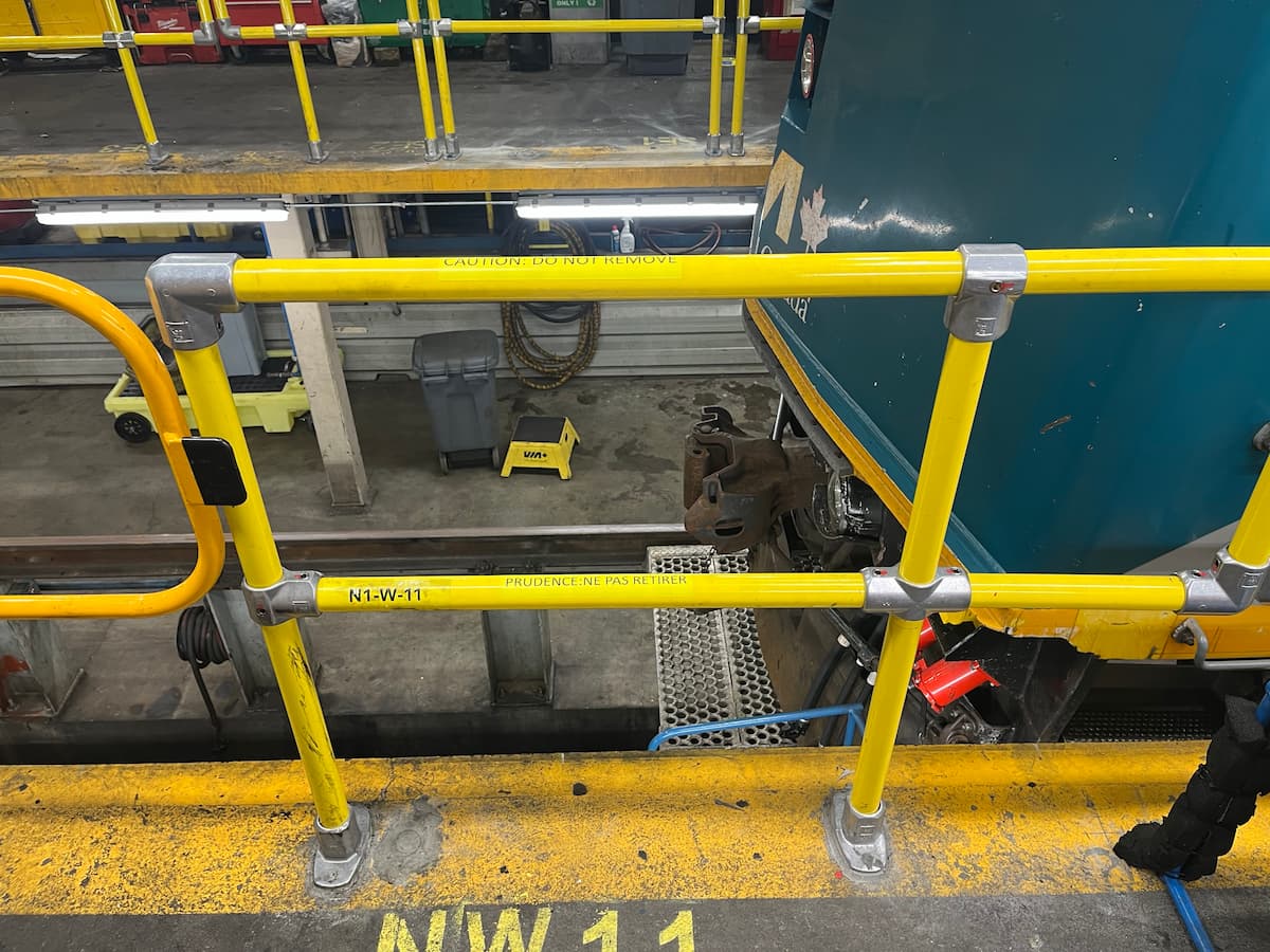 Reinforced guardrail system on an interior rail maintenance platform to improve worker fall protection